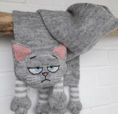 a gray knitted cat with blue eyes hanging on a wall