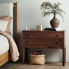 a bedroom with a bed, nightstand and potted plant on the end table next to it