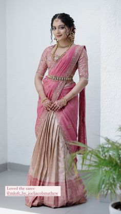 a woman in a pink and gold sari with her hands on her hips, posing for