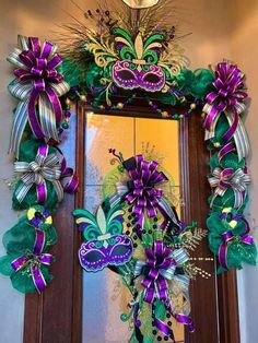 a mardi gras wreath with purple and green ribbons on the front door,