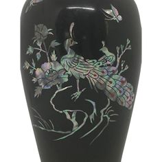 a black vase with a peacock painted on it