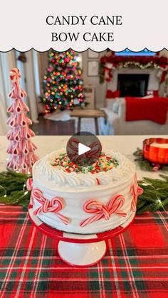 a white cake sitting on top of a table next to a red and green christmas tree