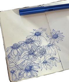 a blue pen is on top of an open notebook with drawings of flowers and leaves