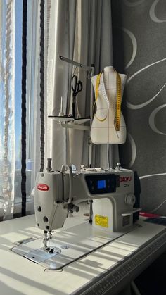 a sewing machine sitting on top of a white table next to a window with curtains