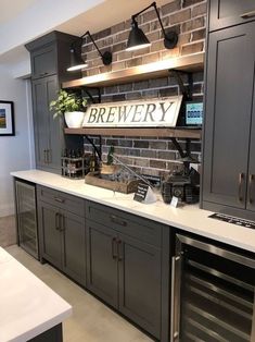 a kitchen with gray cabinets and white counter tops is pictured in this image, there are lights on the brick wall above the sink