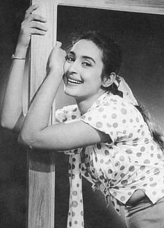 an old photo of a woman leaning up against a wooden wall with her hands on the door