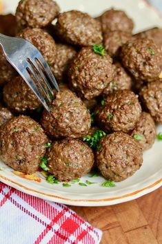 a white plate topped with meatballs on top of a red and white checkered table cloth