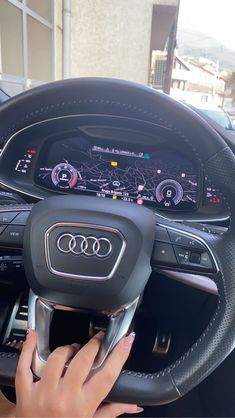 a woman is driving an audi car with her hands on the steering wheel and dashboard