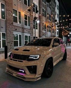 a brown car parked in front of a tall brick building with lights hanging from it's sides