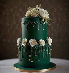 a green and gold wedding cake with white flowers on the top, sitting on a table