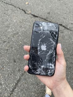 a person holding an iphone with a cracked screen on the back and side of it