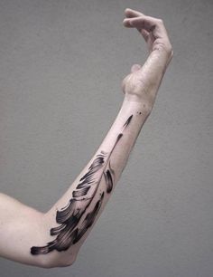 a man's arm with an inked feather tattoo on it