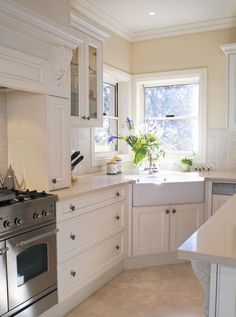 a white kitchen with an oven, sink and counter top space is shown in this image