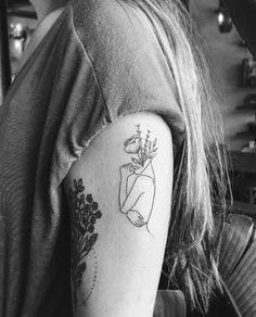 a black and white photo of a woman's arm with a flower tattoo on it