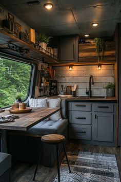 a kitchen area with a table and stools next to a window that looks out onto the woods