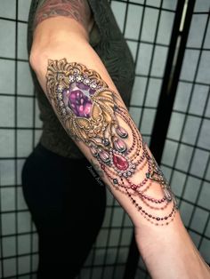 a woman's arm with a tattoo on it that has beads and jewels all over it