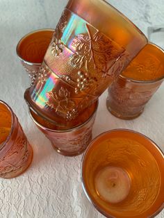 an assortment of glass cups and saucers sitting on a white tablecloth covered table