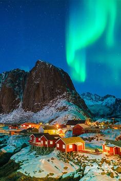 the northern lights shine brightly in the sky above small houses and snow - covered mountains