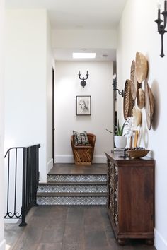 an entry way with stairs and decorative wall hangings on the walls, along with a wooden bench