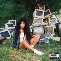 a woman sitting on the ground in front of old tvs and other electronic equipment