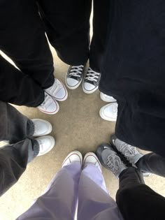 four people standing in a circle with their feet on the ground looking down at them