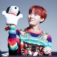 a woman with red hair holding up a stuffed animal