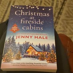 the book christmas at fireside cabins is being held up by someone's hand