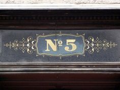 the number five sign is attached to the building's front door and has ornate designs on it