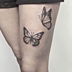 a woman's legs with two butterflies tattooed on the side of her leg,