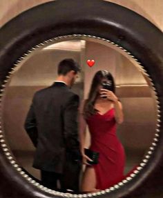 a man and woman are standing in front of a mirror with the reflection of them looking at each other