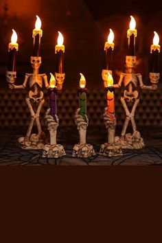 a group of candles sitting on top of a table next to a skeleton figurine