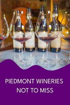 four wine glasses sitting on top of a table with bottles in the background that says, piedmontn wines not to miss