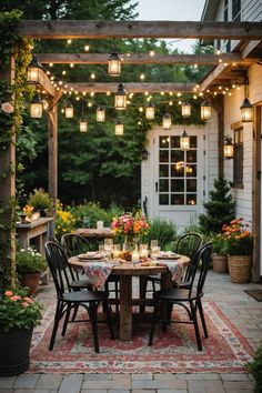 an outdoor dining area with lights strung over the table and chairs, surrounded by potted plants