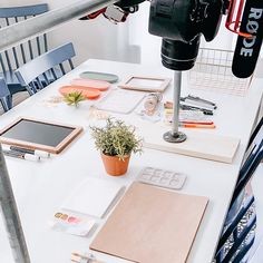 a white table topped with lots of assorted items next to a camera and laptop