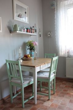 a kitchen table with two chairs and a vase on top of the table next to it