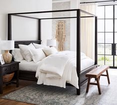 a bed with white linens and pillows in a bedroom next to a wooden bench