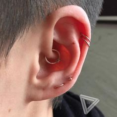 a person with ear piercings on their ears and behind them is a small triangle