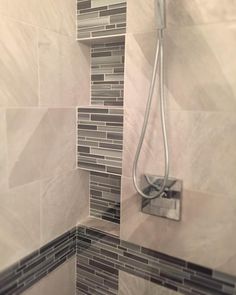 the shower head is mounted to the wall in this tiled bathroom with gray and white tiles