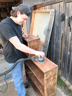 a man is sanding the wood with a power washer in his hand and an old wooden box behind him