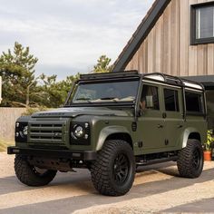 a green land rover parked in front of a building