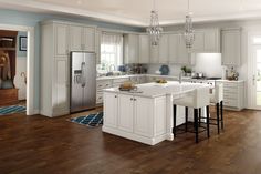 a large kitchen with white cabinets and wood flooring, including an island in the center