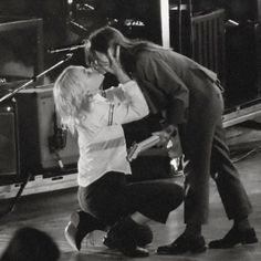 a woman kneeling down next to a man in front of a microphone