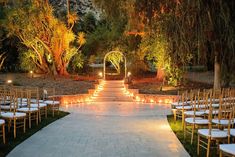 an outdoor wedding venue with rows of chairs and candles lit up on the aisle to the ceremony