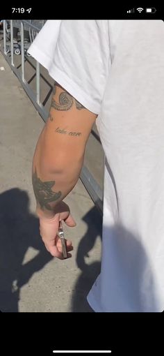 a man with tattoos on his arm holding a cell phone