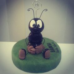 a cake shaped like a bug sitting on top of a green cushion with eyes and legs