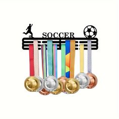 three medals are in front of a soccer trophy with the word soccer on it and a person running behind them