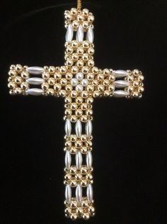 a gold and silver cross ornament on a black background, with beading