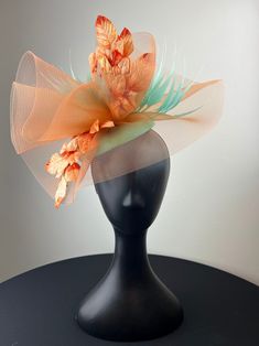 Orange crinoline beautifully shaped atop a mint green button base, accented with a cut mint feathers and ombre velvet leaves. Sits on a comfortable white headband. Ships in a high quality storage box. One of a kind. Perfect for Kentucky Derby, Royal Ascot, church, weddings, just for fun. Kentucky Derby Green Fascinator With Handmade Flowers, Green Fascinator With Handmade Flowers For Spring, Green Spring Fascinator With Handmade Flowers, Green Handmade Flowers Fascinator For Spring, Spring Formal Headpiece With Feathers, Summer Green Feathered Headpiece, Green Feathered Mini Hat For Kentucky Derby, Green Feathered Mini Hat For Royal Ascot, Green Mini Hats With Feathers For Royal Ascot