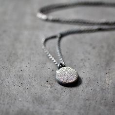 "A delicate 12mm (about 1/2\") round quartz druzy cabochon with a silvery gray titanium diffused coating set in a hand fabricated bezel of fine and sterling silver and oxidized for an organic, mysterious effect. The sterling silver cable chain necklace drapes a petite 18\" in length including the sterling lobster clasp. This necklace is made to order and will be sent out within 5 weeks. **The oxidation is not permanent, but will wear out uniquely with each owner like a pair of jeans.** All jewel Minimalist Round Oxidized Jewelry, Silver Moon Phase Round Disc Jewelry, Silver Moon Phase Disc Jewelry, Minimalist Necklaces With Oxidized Finish, Minimalist Necklace With Oxidized Finish, Minimalist Round Necklace With Oxidized Finish, Gray Round Jewelry For Gift, Gray Round Jewelry Gift, Gray Stainless Steel Jewelry For Gifts