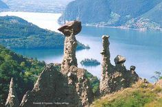 an image of some rocks in the middle of a field with water and mountains in the background